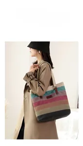 Side view of woman carrying a large canvas tote bag with five-color striped patchwork design
