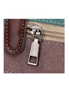 Detailed view of canvas tote bag featuring premium metal zipper and brown leather trim accents
