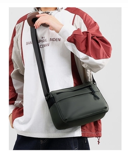 Detail of dark green waterproof crossbody bag showing double zippers and front pocket