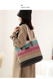 Detail shot of multi-colored striped canvas tote bag worn on shoulder in minimalist interior