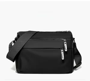 Front view of black waterproof messenger bag with multiple zippers and wide strap