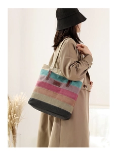 Detail of colorful striped canvas tote bag with brown leather handle and embossed logo