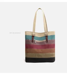 Detail of multi-color striped canvas tote bag showing the textured stitching and leather handle