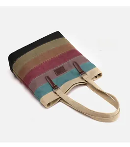 Detail of colorful striped canvas tote bag with leather logo patch and reinforced handles