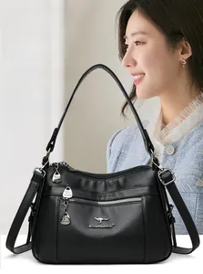 Close-up of black lychee grain leather handbag with dual front zipper pockets and logo