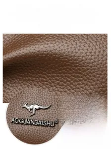 Close-up of brown litchi grain leather texture with premium silver metallic logo