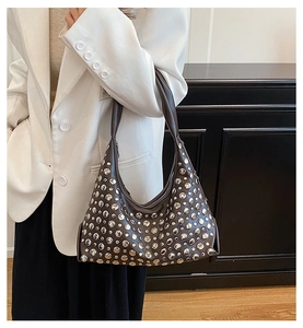 Detail of dark brown leather hobo bag featuring polished silver metal rivet studs