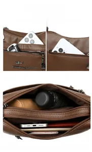 Macro detail of brown pebble leather bag showing multiple compartments and zip pockets