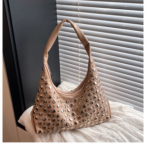Detail shot of silver metal rivets on a beige leather hobo bag with a soft texture