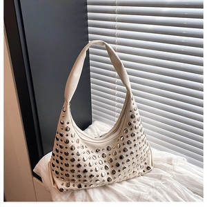 Detail of cream hobo bag featuring decorative silver rivets and smooth zipper closure