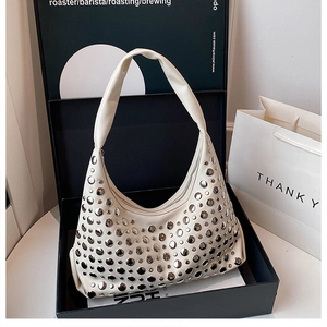 Detail of cream white half-moon bag with silver round rivets in a luxury gift box