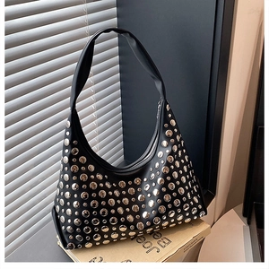Detailed close-up of a black leather hobo bag with silver metallic rivet decorations