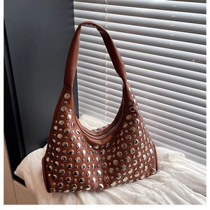 Detail shot of brown hobo bag featuring decorative silver rivets and sleek leather texture