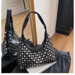 Close-up of a black leather underarm hobo bag with trendy silver rivet embellishments