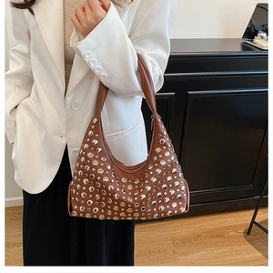 Close-up of brown leather underarm bucket bag featuring decorative silver metal rivets