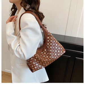 Close-up of brown leather hobo bag with silver studs worn as a stylish underarm bag