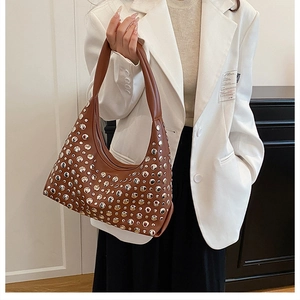 Detail of brown hobo bag with gold and silver rivets and sturdy shoulder strap