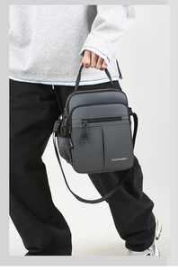 Detail of dark grey waterproof oxford shoulder bag with multiple zipper pockets and handle