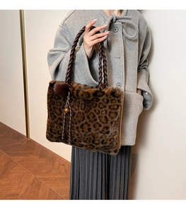 Detail of leopard print faux fur tote bag with braided handle and plush ball charm