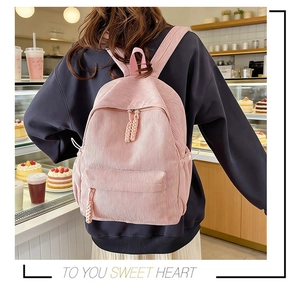 Pink corduroy backpack close-up with woven zipper detail and soft fabric texture