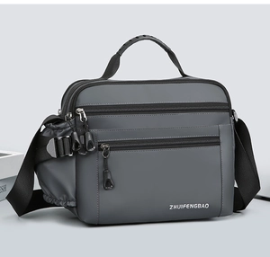 Detail of dark grey waterproof nylon messenger bag featuring multiple zipper compartments