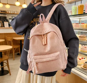 Detail of pink corduroy backpack featuring woven zipper pulls and soft striped texture