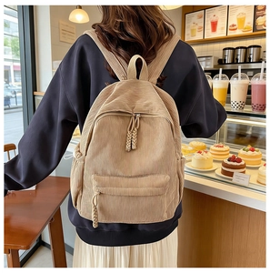 Close-up of minimalist corduroy backpack showing textured fabric and side drawstring pocket