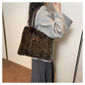 Detail of leopard print plush tote bag with woven strap and decorative pompom charms