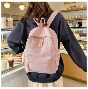 Detail of pink corduroy backpack featuring ribbed texture and braided zipper pulls