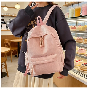 Detailed texture of pink corduroy backpack with dual zipper and side pockets for travel