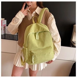 Close-up of grass green corduroy backpack with front pocket and textured fabric details