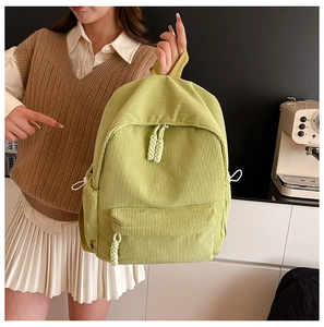 Close-up of light green corduroy backpack with woven zipper detail and soft texture