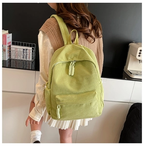 Detail showing mint green corduroy backpack with woven rope zipper and textured fabric