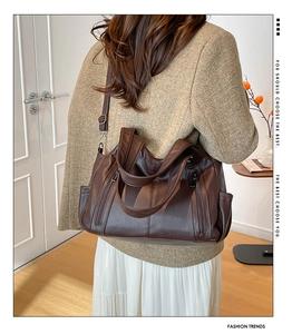 Detailed view of dark brown pebbled leather tote bag with functional zippers and side pockets