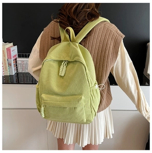 Detail of light green corduroy backpack with woven rope zipper pulls and side pockets