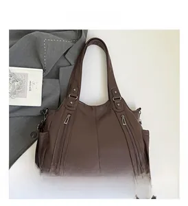 Detail of dark brown leather tote bag with lychee texture and decorative zippers