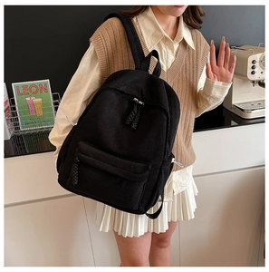 Detailed view of the black corduroy fabric texture and front pocket on this casual backpack