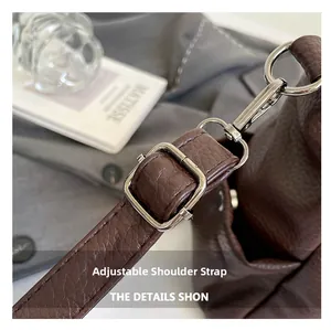 Close-up of adjustable silver buckle strap on brown lychee texture leather tote bag