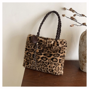 Detail of leopard print faux fur tote bag with braided handles and a plush pompom charm