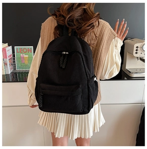 Detail of minimalist black corduroy backpack with front pocket and drawstring side pockets