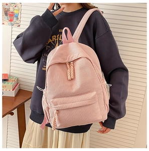 Close-up of pink corduroy backpack featuring woven zipper pulls and side drawstring pockets