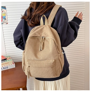 Detail of khaki corduroy backpack featuring side drawstrings and front zipper pocket