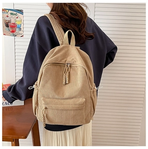 Detail view of corduroy texture and woven zipper pull on a khaki campus backpack