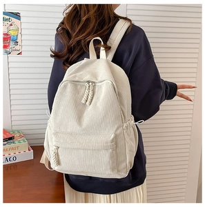 Detail of off-white corduroy backpack on model with large main compartment and front pocket