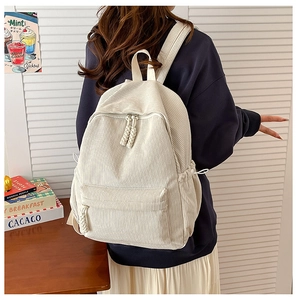 Detail of white corduroy backpack texture with woven zipper pulls and side pockets