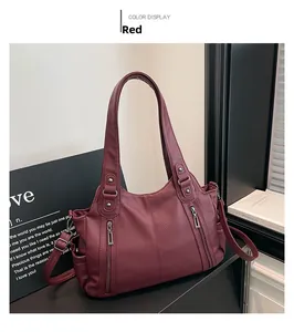 Detail of red pebbled leather tote bag with vertical zippers and side pocket on desk