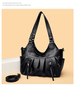 Detail view of black pleated leather tote bag with tassel zippers and shoulder strap