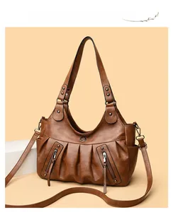 Detail of vintage brown pleated tote bag featuring functional zippers and round logo plaque