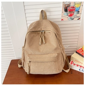 Detailed close-up of khaki corduroy backpack texture with woven rope zipper pulls