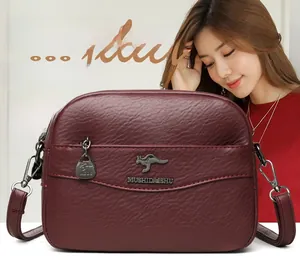Dettaglio ravvicinato della borsa in pelle bordeaux testurizzata con logo a canguro